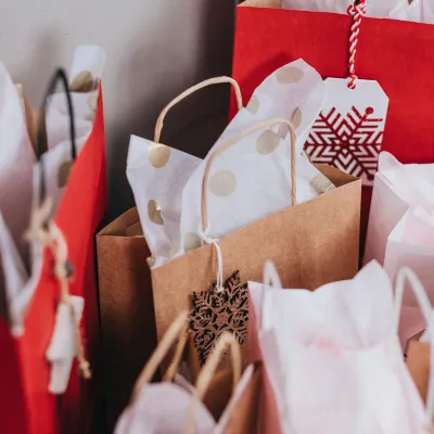 Assorted festive gift bags with tissue paper and holiday-themed tags ready for celebration and gift giving.