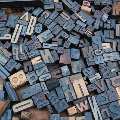 Assorted vintage wooden letterpress blocks scattered on a surface, showcasing various letters and numbers.