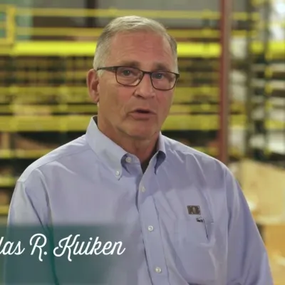 Portrait of Douglas R. Kuiken, President of Kuiken Brothers, in a warehouse setting with shelves in background.