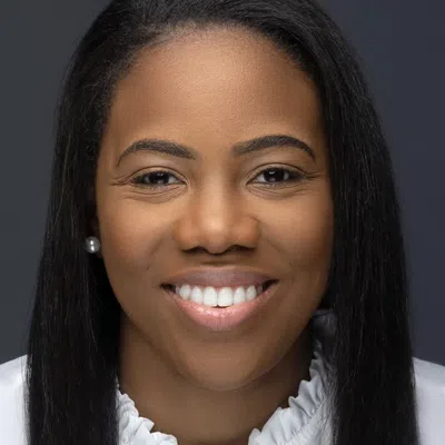Portrait of a smiling woman with long straight hair wearing a white blouse against a dark background