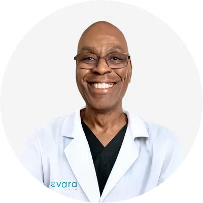 Smiling male healthcare professional in glasses wearing white lab coat and black scrubs against white background