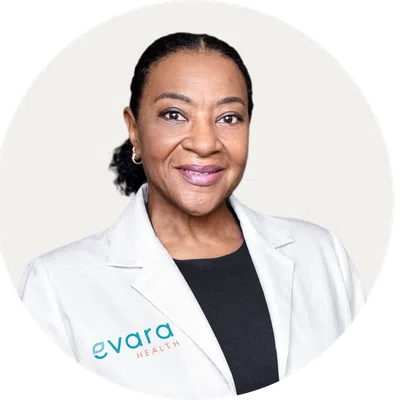 Confident female healthcare professional wearing white coat with Evara Health logo on a white background.