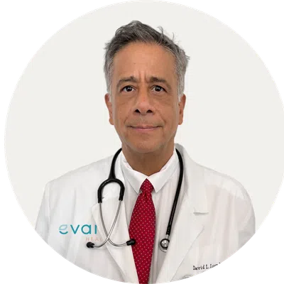 Middle-aged male doctor in white coat with stethoscope and red tie, looking at camera on white background.