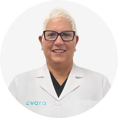 Smiling medical professional with short white hair and glasses wearing an Evara Health white lab coat.