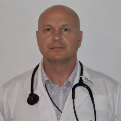Portrait of a bald male doctor wearing a white coat and stethoscope against a plain background
