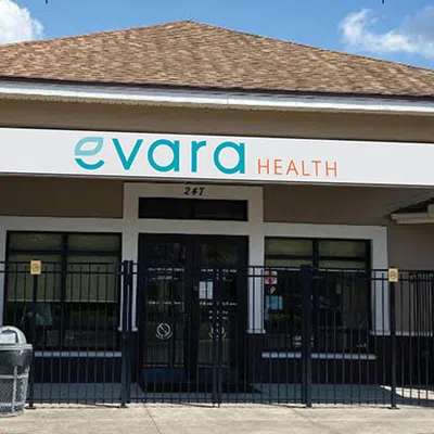 Evara Health sign with teal and orange text displaying contact number and slogan in outdoor setting
