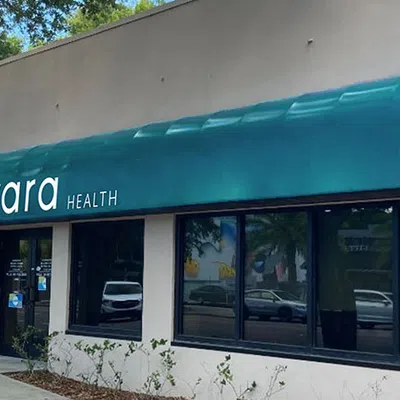Exterior of Evara Health clinic with teal awning and large front windows on sunny day