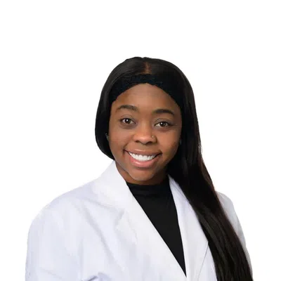 Smiling woman with long black hair wearing a white lab coat and black headband on white background