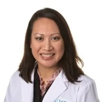 Portrait of a smiling female healthcare professional wearing a white lab coat with logo on a white background