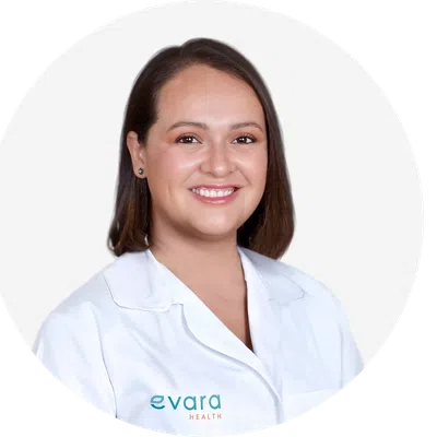 Smiling female healthcare professional wearing a white lab coat with Evara Health logo on a white background.