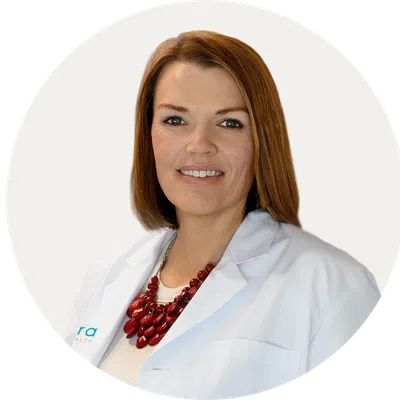 Professional woman with red hair wearing a white lab coat and red necklace on a white background.