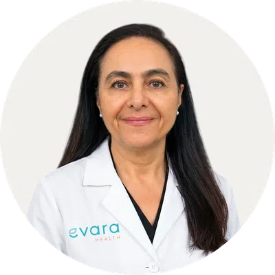 Female healthcare professional with long dark hair in white lab coat smiling against a plain background