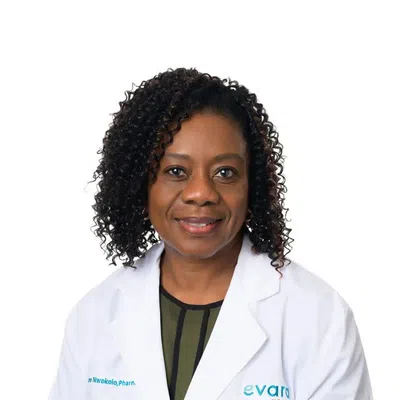 Smiling female pharmacist with curly hair wearing a white lab coat against a white background