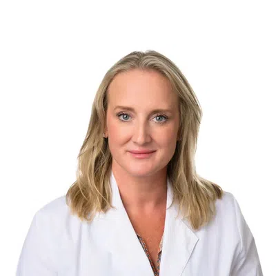 Professional woman with blonde hair wearing a white lab coat against a white background