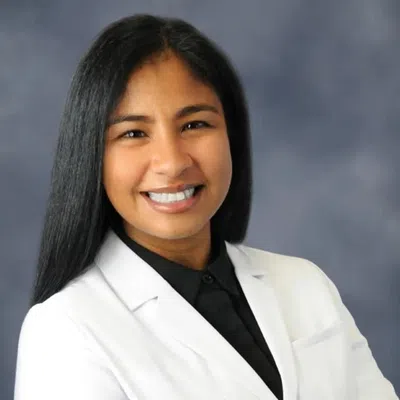 Smiling female healthcare professional wearing a white coat with Evara Health logo against a blue background.