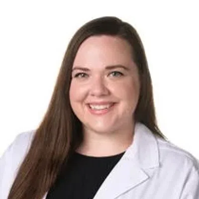 Smiling female healthcare professional wearing a white coat with Evara Health logo on white background