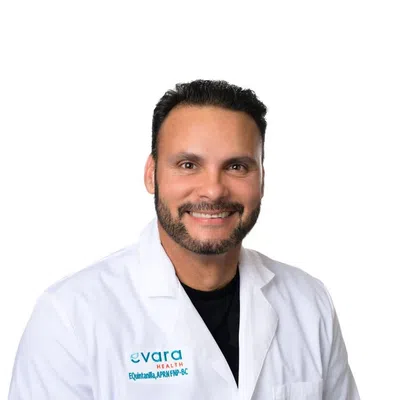 Smiling male healthcare professional wearing a white lab coat with evara Health logo on a white background