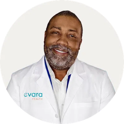 Smiling doctor in white coat with Evara Health logo on blue circular background.