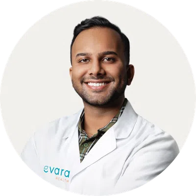 Smiling male healthcare professional wearing a white lab coat with evara health logo on a white background