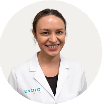 Smiling female healthcare professional wearing Evara Health white lab coat on a light background