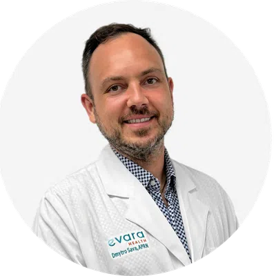 Smiling male healthcare professional wearing white lab coat with Evara Health logo and name tag