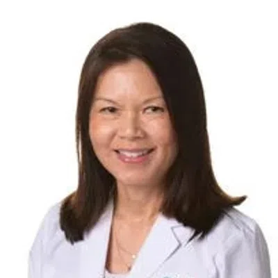 Smiling female healthcare professional in white lab coat with Evara Health logo on chest against white background