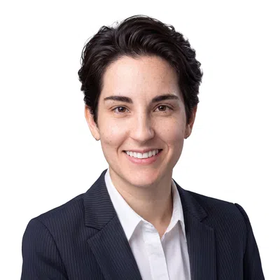 Professional young woman with short dark hair in a pinstripe suit and white shirt smiling against white background