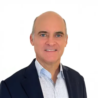 Smiling middle-aged man wearing a dark blazer and checkered shirt on a white background