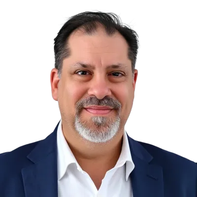 Middle-aged man with salt-and-pepper beard wearing a navy blue blazer and white shirt smiling at the camera