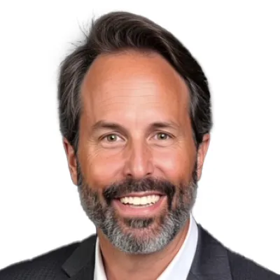 Smiling middle-aged man with gray beard wearing a dark gray suit and white shirt against white background