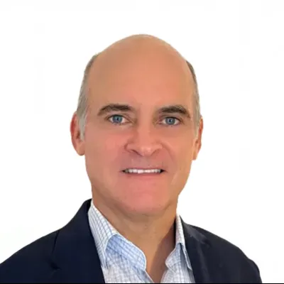 Smiling middle-aged man wearing a dark blazer and checkered shirt on a white background