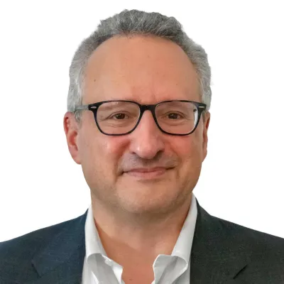 Professional middle-aged man wearing glasses and a suit smiling against a white background