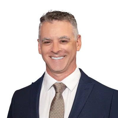 Smiling professional man wearing a dark suit and striped tie against a white background