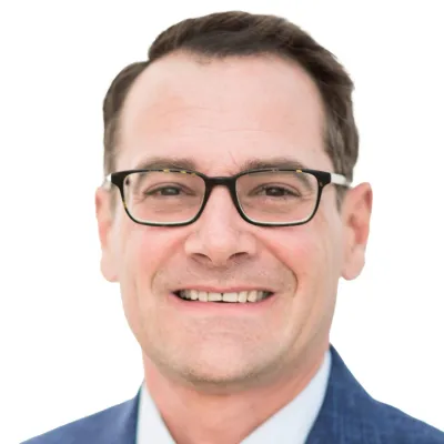 Smiling man wearing black glasses and a blue suit jacket on white background