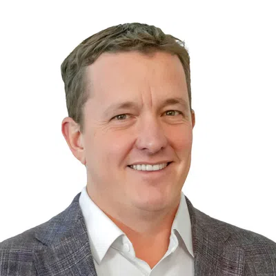 Smiling man in a gray plaid blazer and white shirt on a white background, head and shoulders portrait.