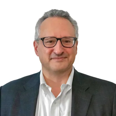 Professional middle-aged man wearing glasses and a suit smiling against a white background