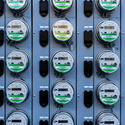 Rows of digital electric meters installed on a gray metal panel for energy monitoring and measurement.