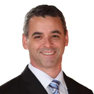 Smiling professional man wearing a dark suit and striped tie against a white background