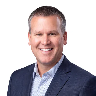Smiling professional man in checkered shirt and navy blue blazer against white background