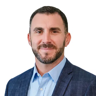 Portrait of a confident man with a beard wearing a blue checkered blazer and light blue shirt on white background