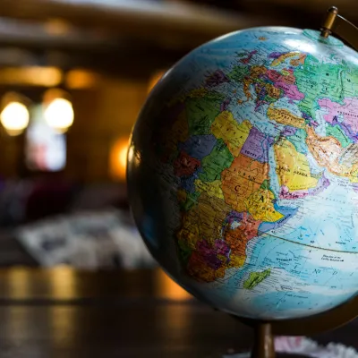 Close-up of a colorful globe showing Africa, Europe, and Asia on a wooden table indoors.
