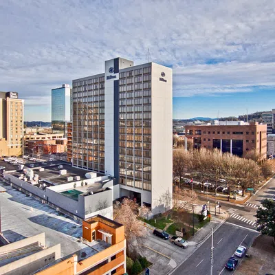 Downtown cityscape featuring Hilton hotel building, surrounding offices, streets, cars, and a partly cloudy sky.