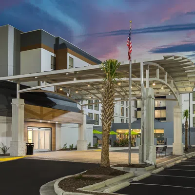 DoubleTree by Hilton hotel exterior at sunset with entrance canopy and American flag in clear sky.