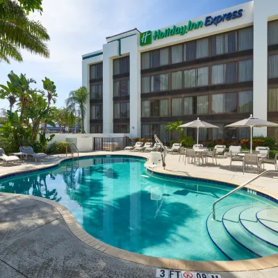 Outdoor swimming pool at Holiday Inn Express with lounge chairs and umbrellas on a sunny day