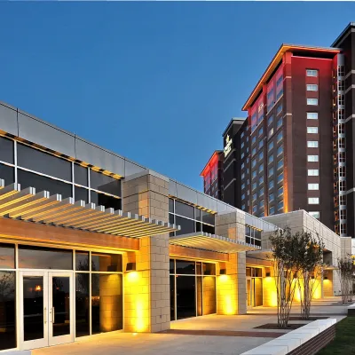 Exterior view of Overton Hotel at dusk with illuminated modern facade and tall tower under clear blue sky