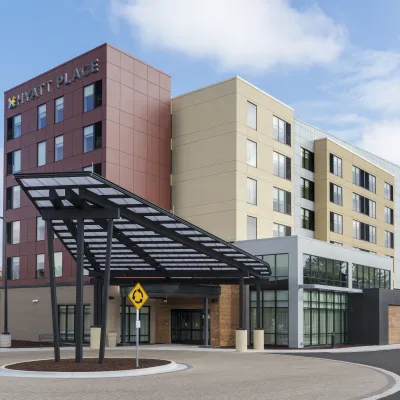 Modern Hyatt Place hotel building with large entrance canopy under blue sky and landscaped surroundings