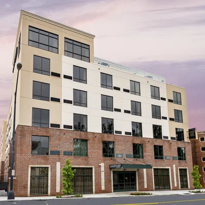 Modern mixed-material building with brick and white facade under a colorful purple sunset sky.