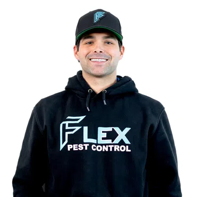 Smiling man wearing a black Flex Pest Control hoodie and cap against a white background.