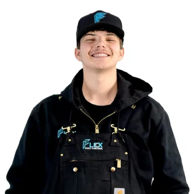 Smiling pest control worker wearing black Flex Pest Control uniform and cap standing with hands in pockets.