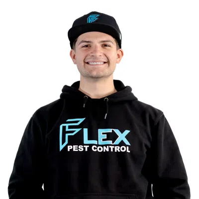 Smiling man wearing black Flex Pest Control hoodie and cap against white background.